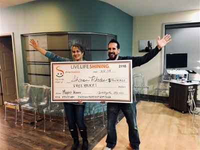Two people holding a big check with their arm up 
