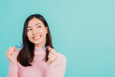 Woman smiling holding a retainer in both hands 